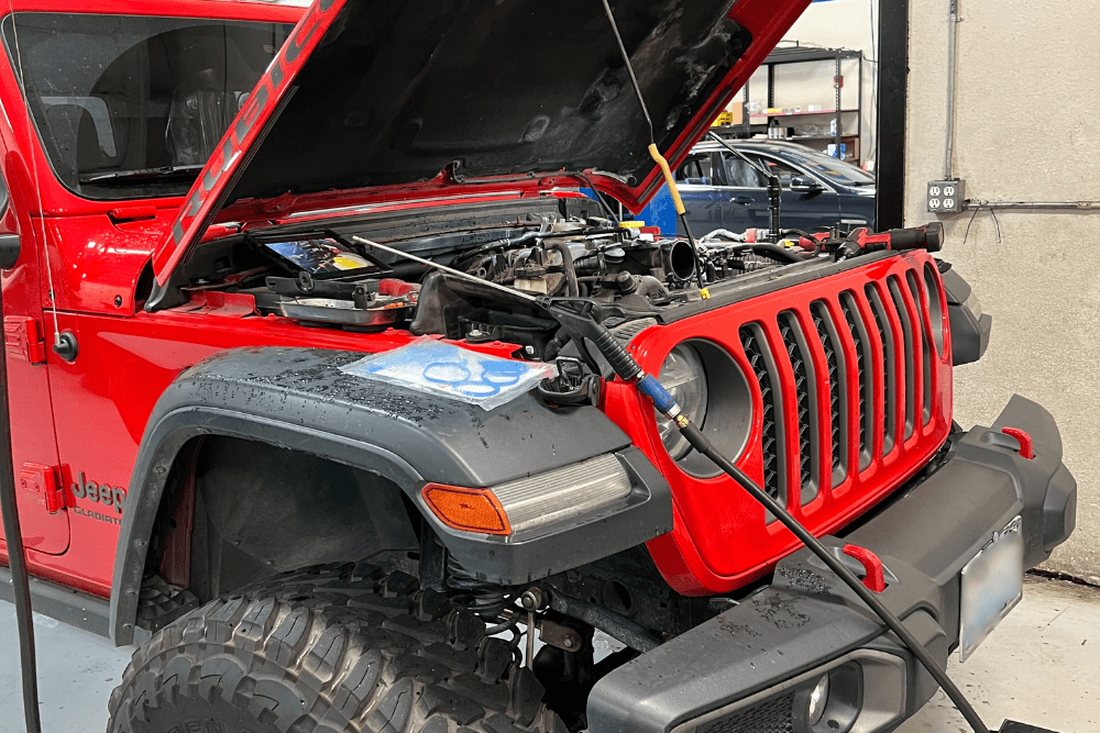 jeep engines and transmissions, auto repair in Morgan Hill, CA at C&M Auto Service, Inc. , Red Jeep Rubicon in a repair shop with its hood open, undergoing engine diagnostics and service.