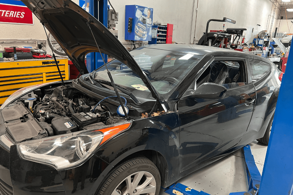 Car noises, auto repair in Morgan Hill, CA by C&M Auto Service Inc. A black car undergoing inspection in a modern auto repair shop, representing professional diagnostics, hybrid and EV repair, and full-service automotive care.