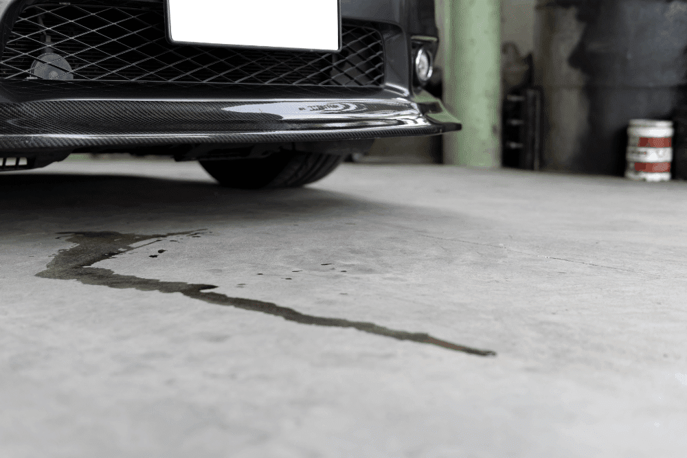 Fluid leak, auto repair in Morgan Hill, CA by C&M Auto Service.Image of a vehicle in the shop with fluid leaking onto the floor, highlighting professional inspection and repair for oil or coolant leaks to protect engine performance.