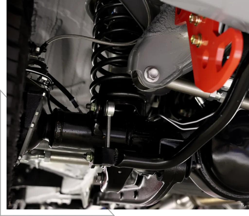 Close-up view of a vehicle’s suspension system, featuring metal springs, bolts, and a red bracket—showcasing the intricate details often addressed during Suspension Repair & Service in Morgan City.